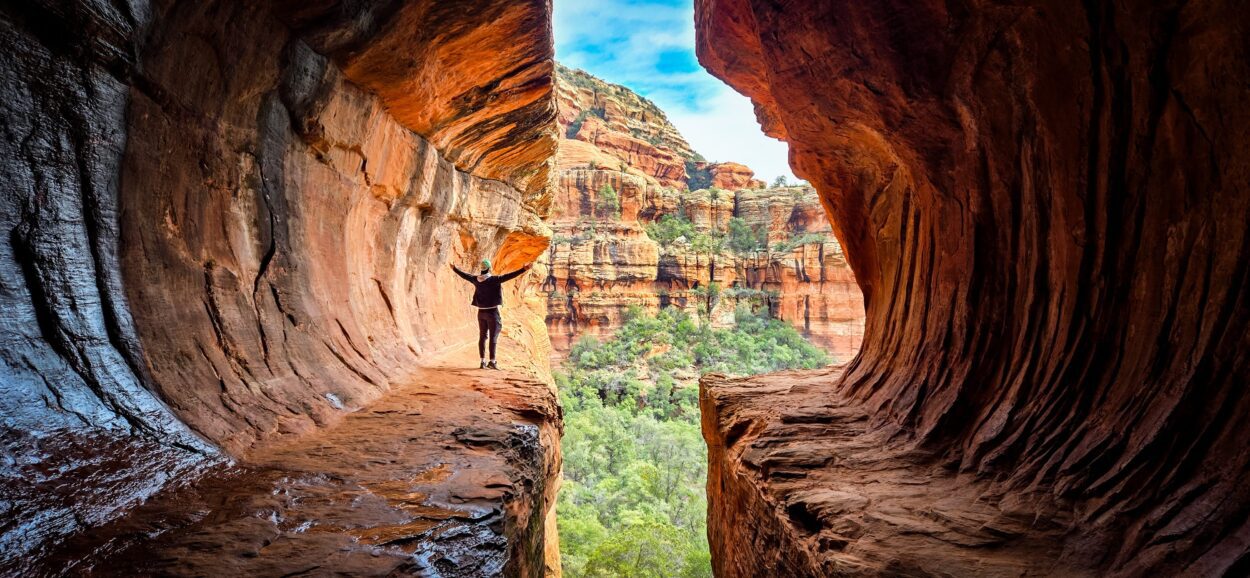 Current image: man stood in cave between rocks