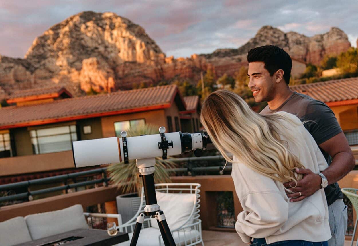 Couple looking through telescope with red rocks in the background at the Wilde Resort and Spa